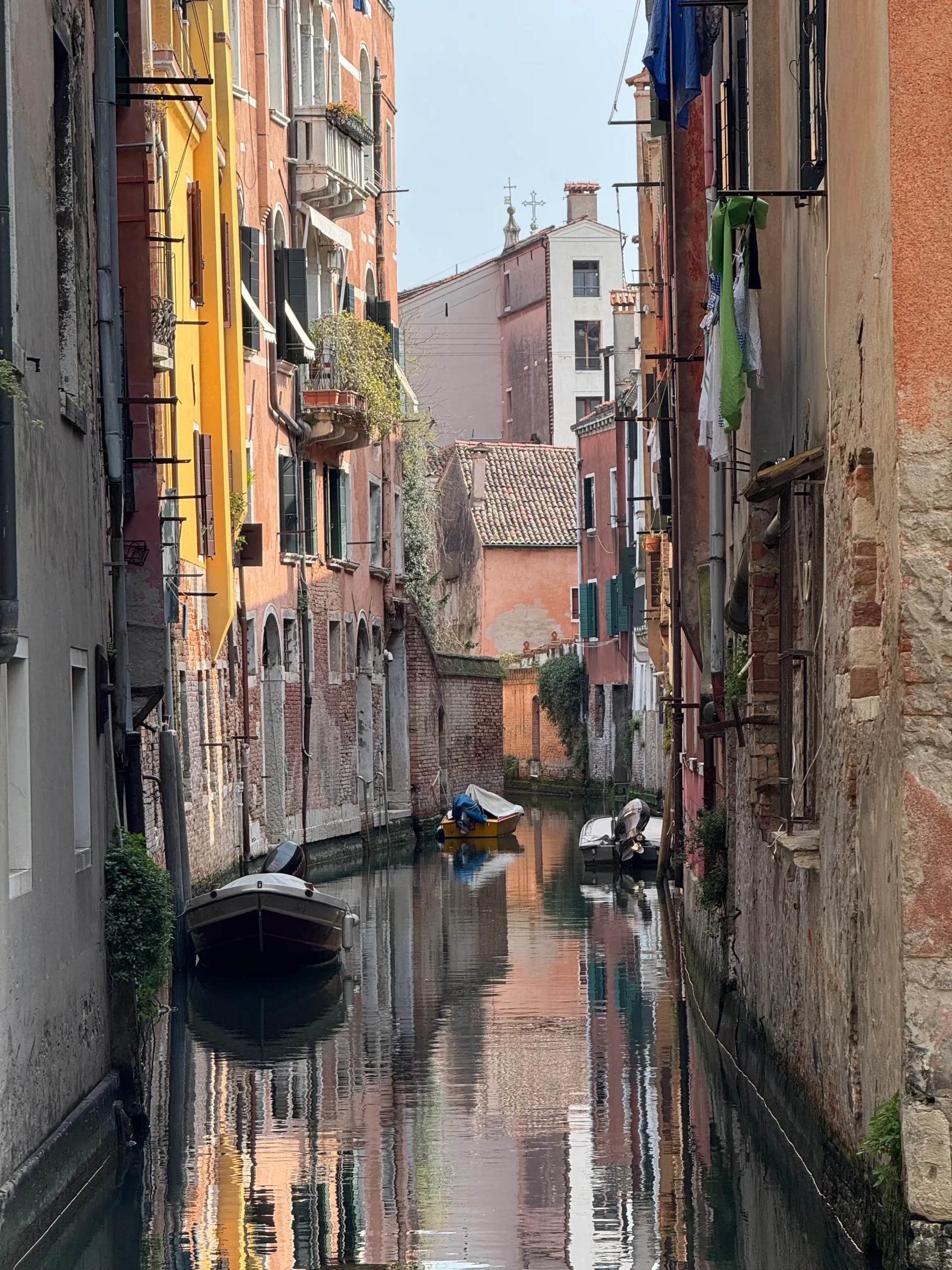 Romantiškas Venecijos kanalas su valtimis ir spalvingų namų atspindžiais vandenyje