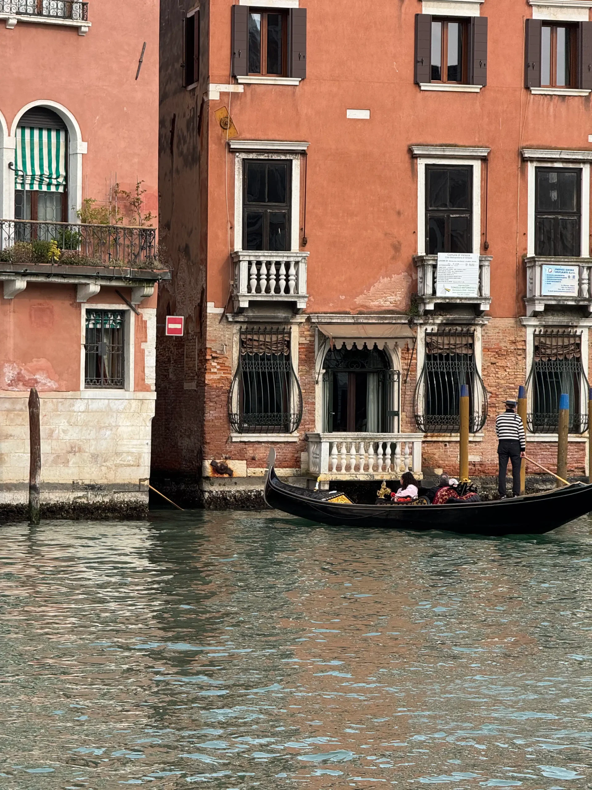  Gondolininkas tradiciniais drabužiais plukdo gondolą pro seno rūmų fasadą Didžiajame kanale