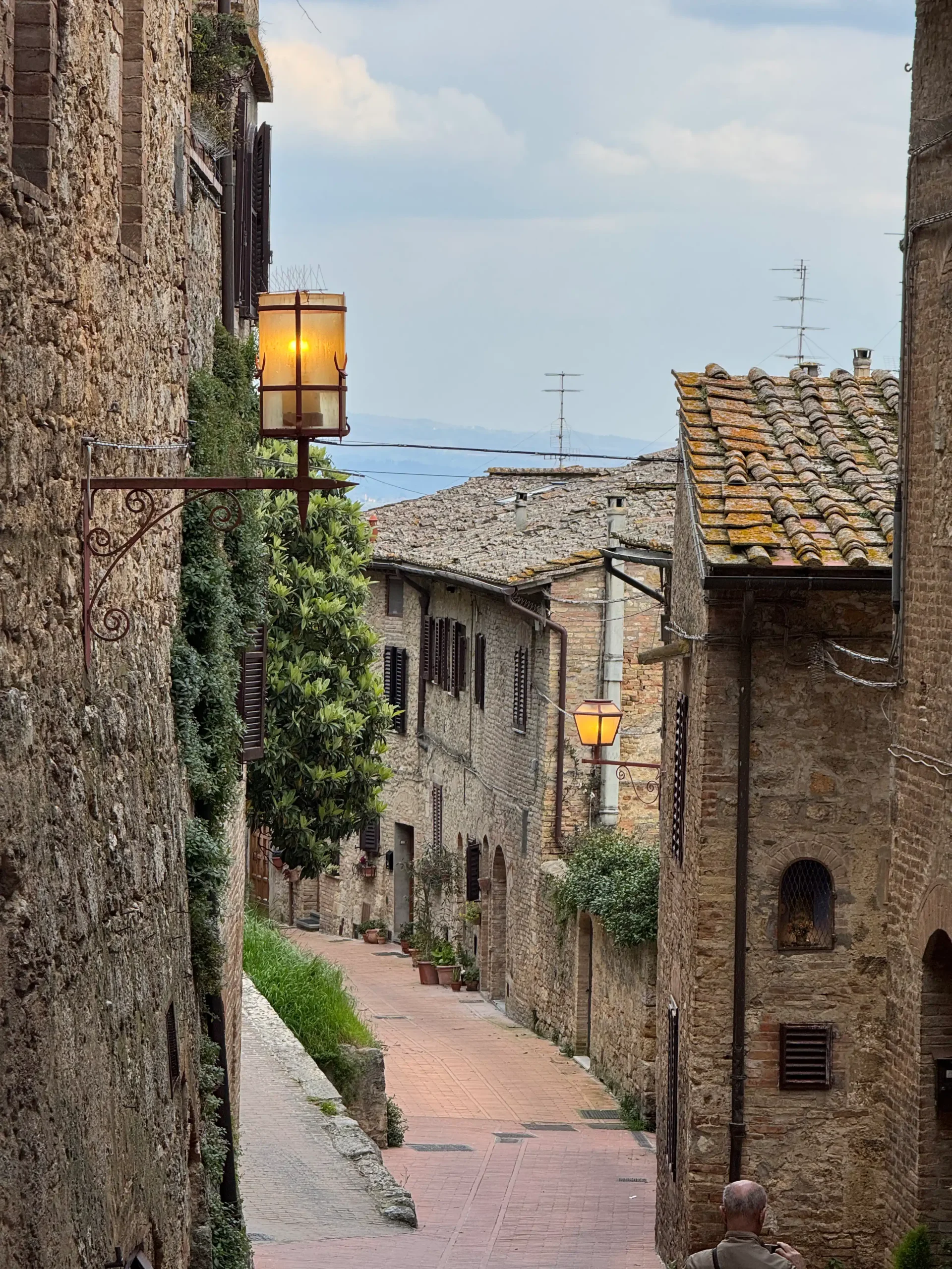 Toskana su kūdikiu: 4 naktys Chianti regione (patirtis 2026) San Gimignano gatvė vakare — viduramžių bokštų miestas Toskanoje
