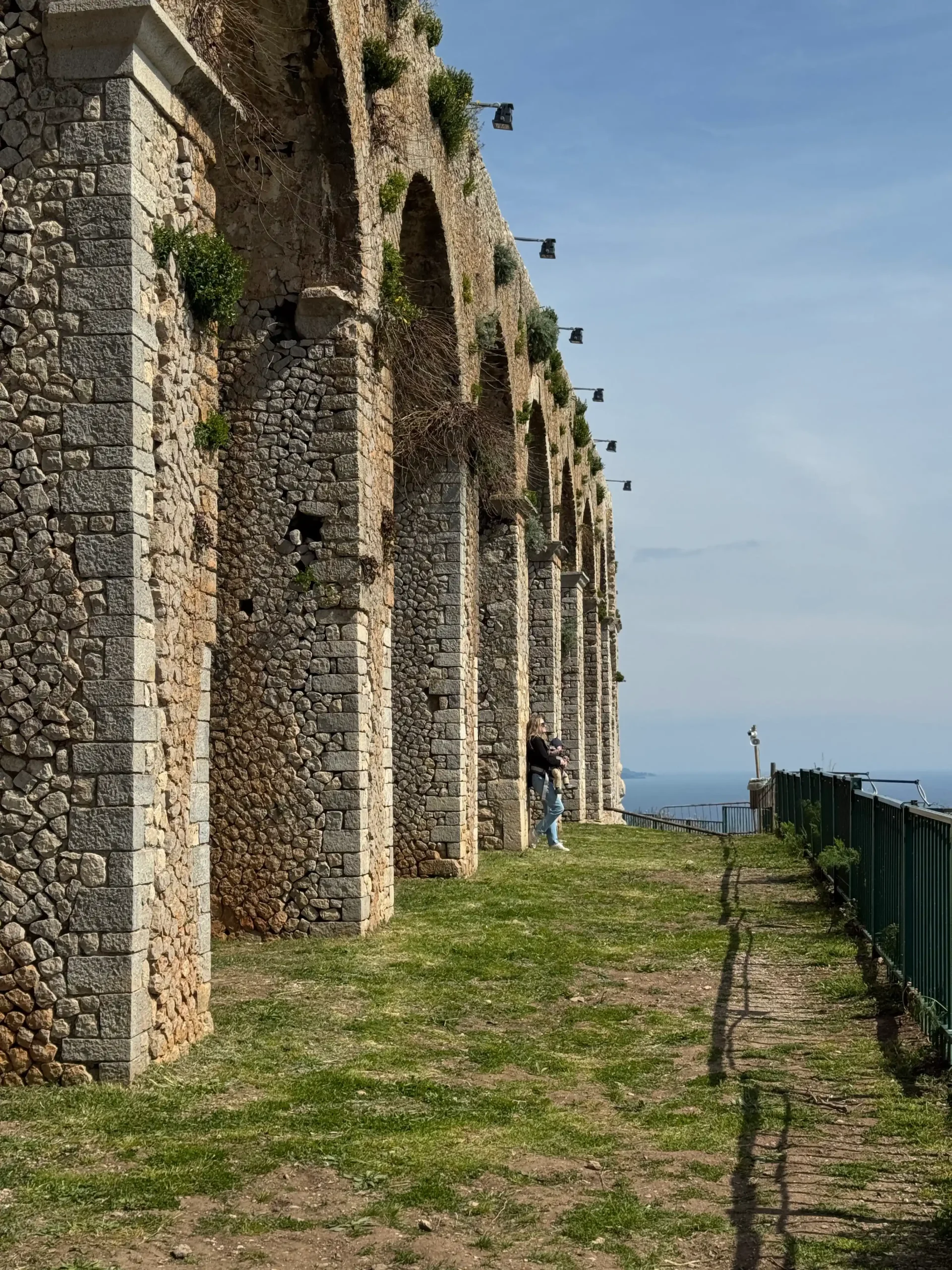 Mama su kūdikiu prie senovinių pilies arkų virš jūros — Sperlonga pilies Grotto di Tiberio akveduko arkados