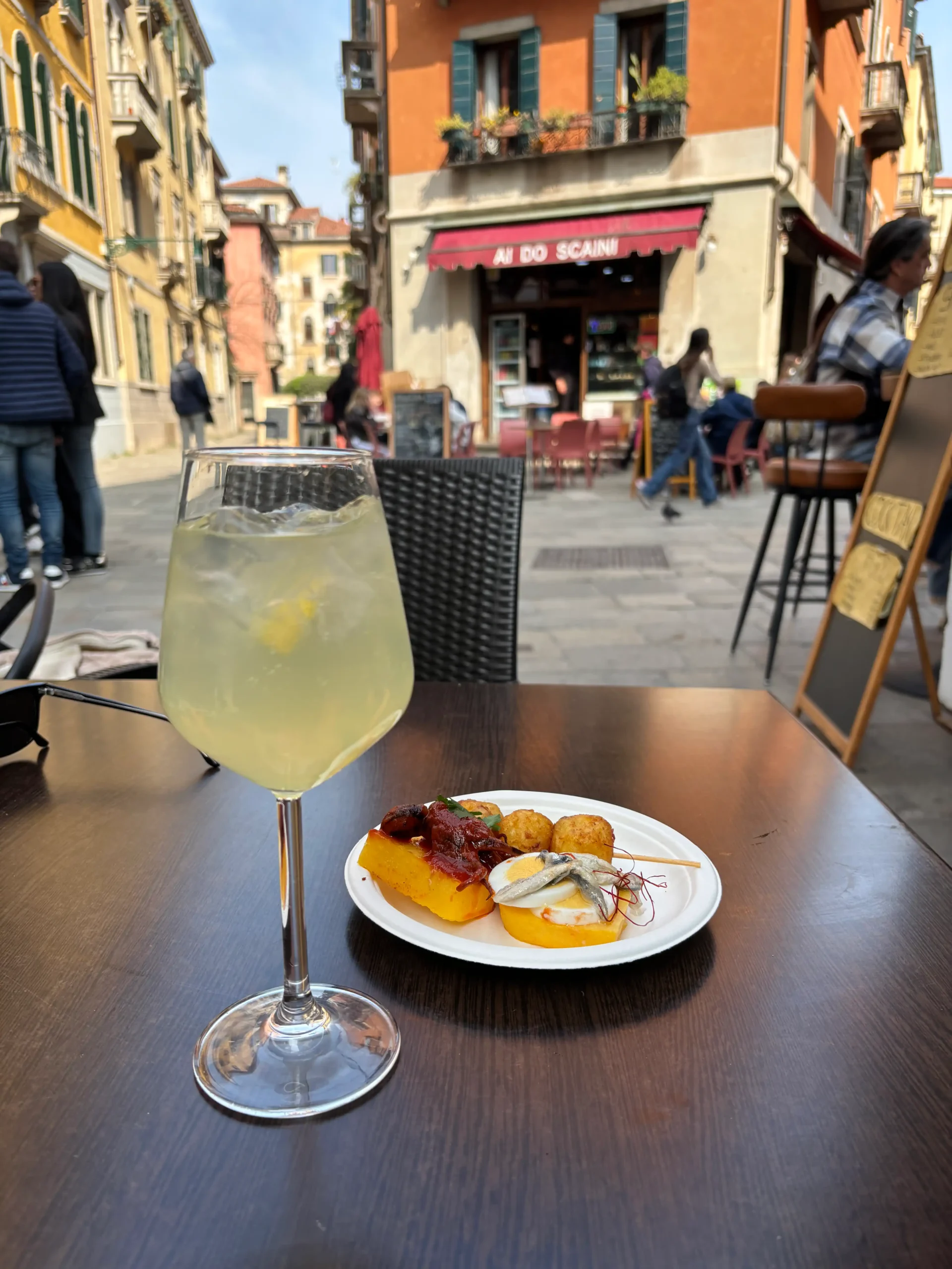 Aperol Spritz ir cicchetti lėkštutė su ančiuviais lauko kavinėje Venecijos aikštėje