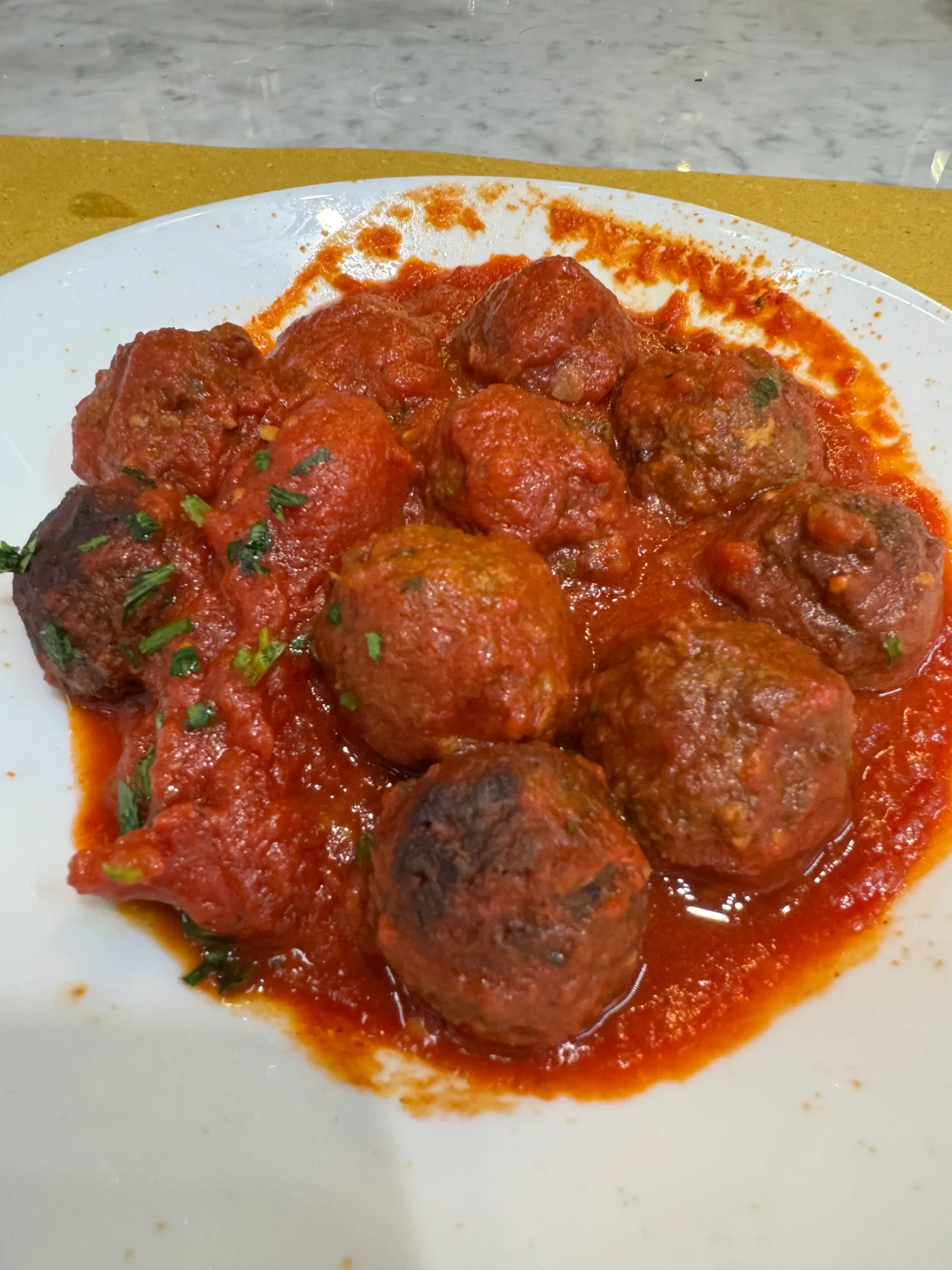 Toskana su kūdikiu: 4 naktys Chianti regione (patirtis 2026) Itališki mėsos kukuliai (polpette) ryškiame pomidorų padaže su šviežiomis žolelėmis, baltoje lėkštėje
