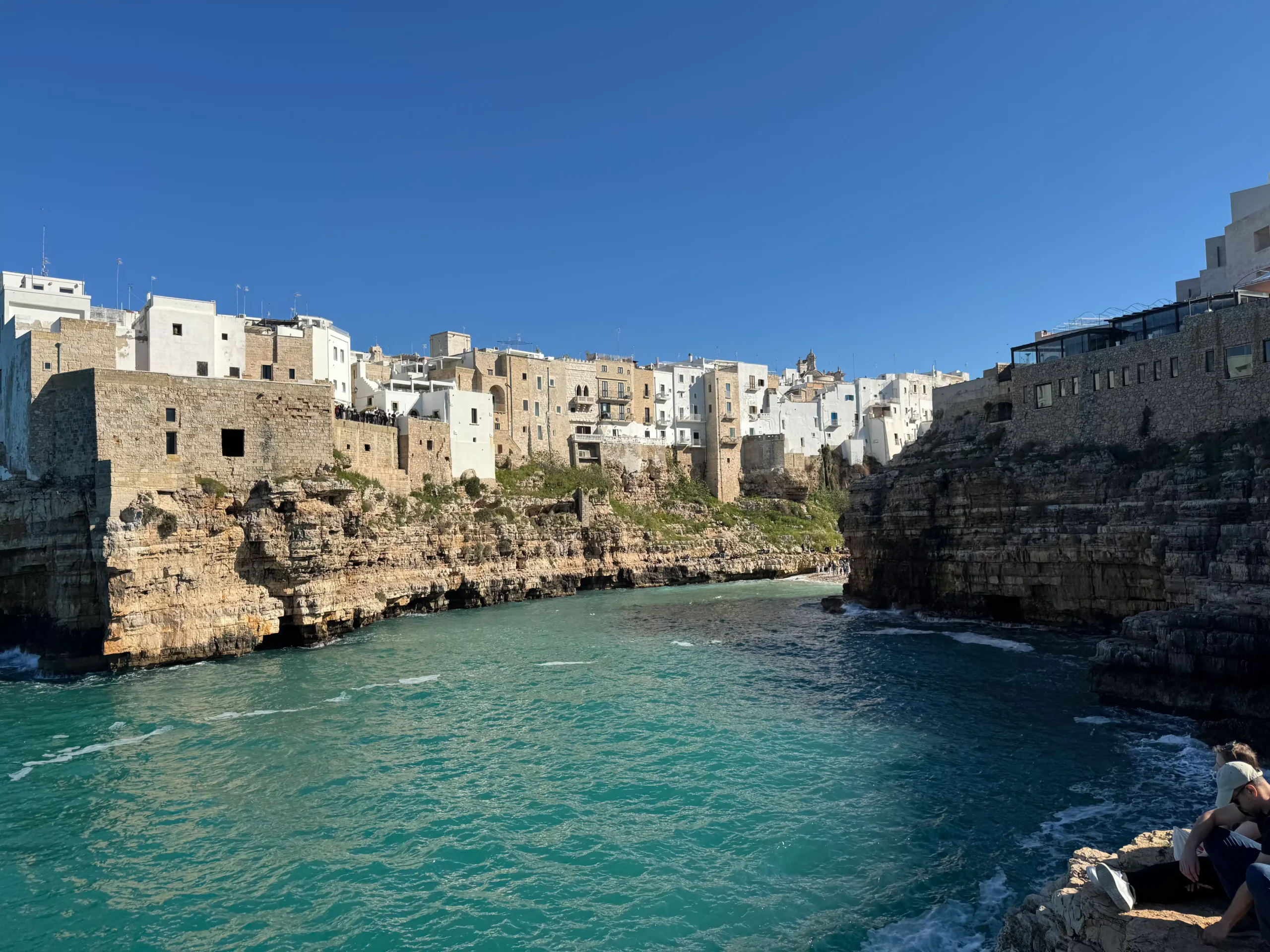 Polignano a Mare senojo miesto gynybinės sienos ir pastatai virš turkio spalvos jūros įlankos saulėtą dieną