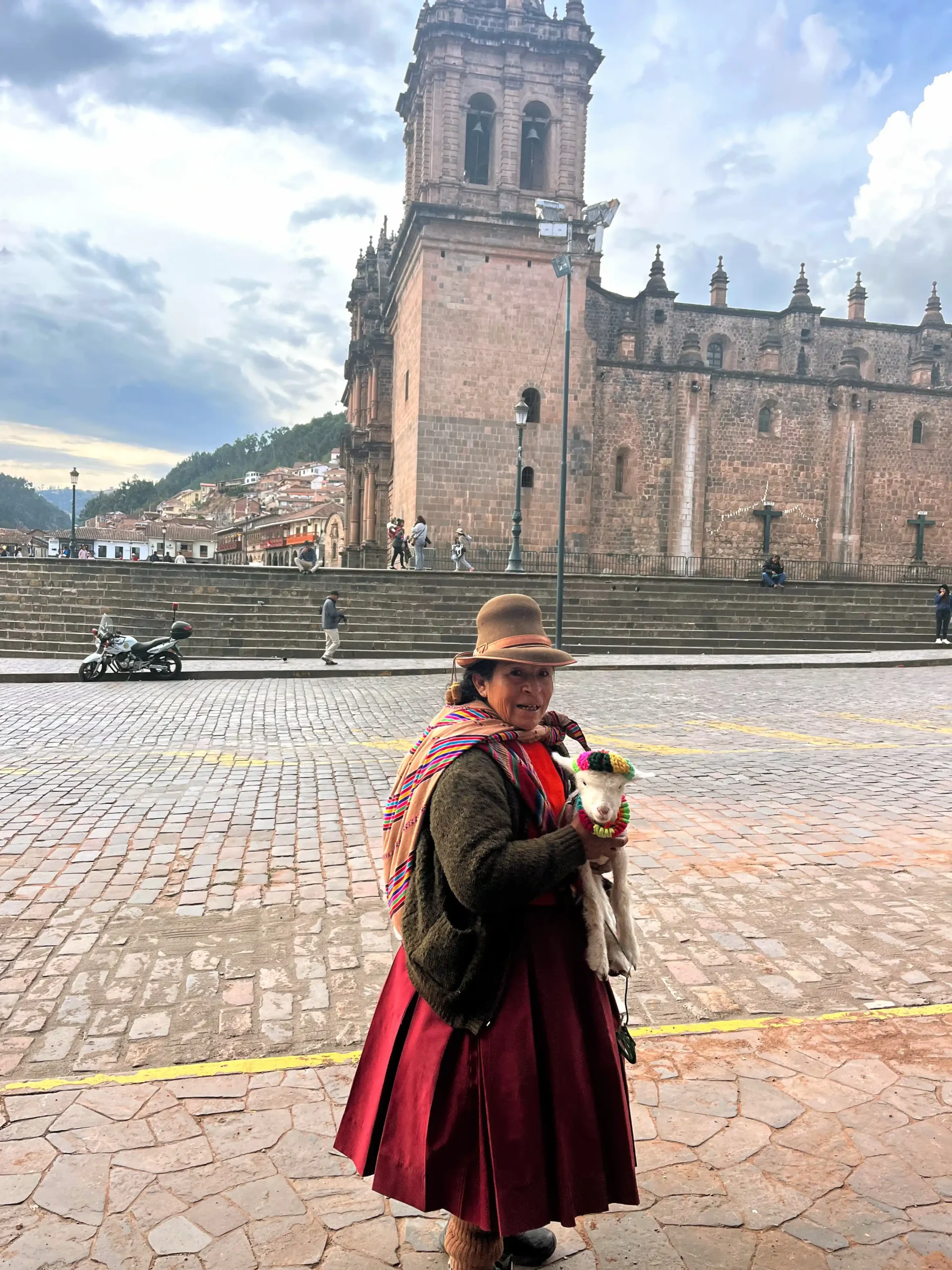 Peru moteris tradiciniais drabužiais laiko avinėlį Plaza de Armas aikštėje prie Kusko katedros