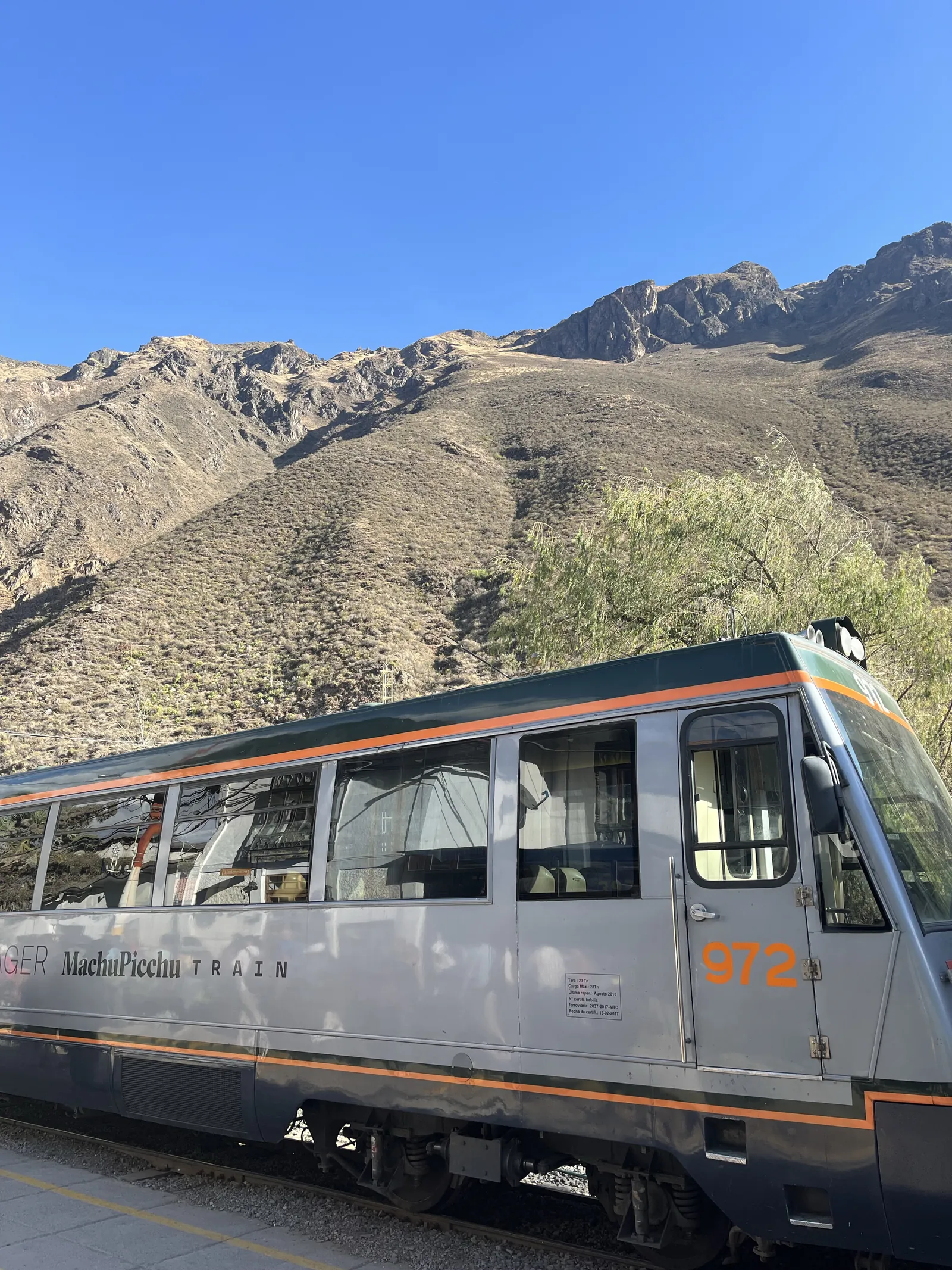 Sidabrinis „Machu Picchu Train" traukinys Nr. 972 stotyje, fone – pliki Anų kalnai giedrą dieną