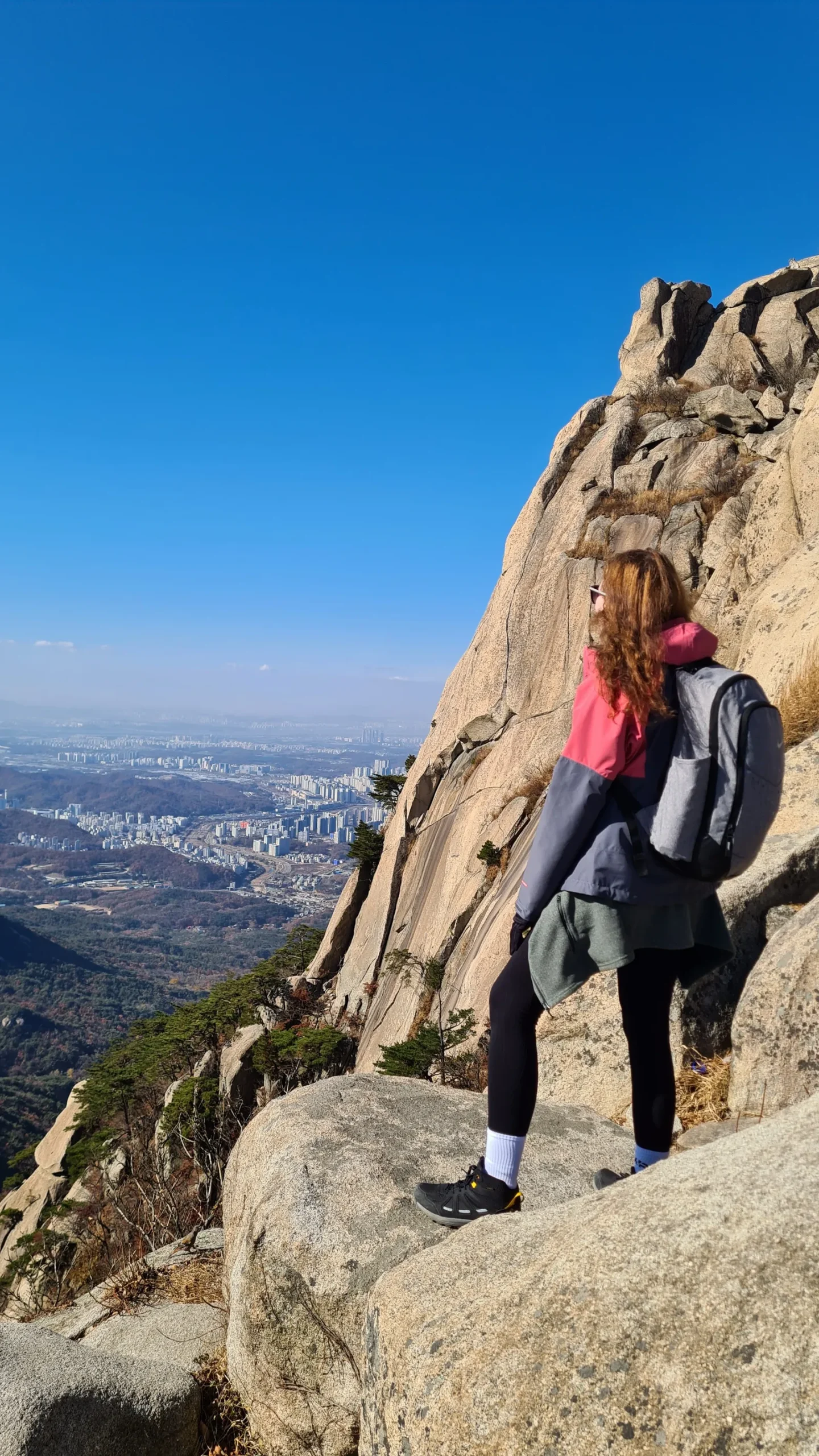 Moteris su kuprine ant Bukhansano kalno granito uolų, apačioje – Seulo panorama
