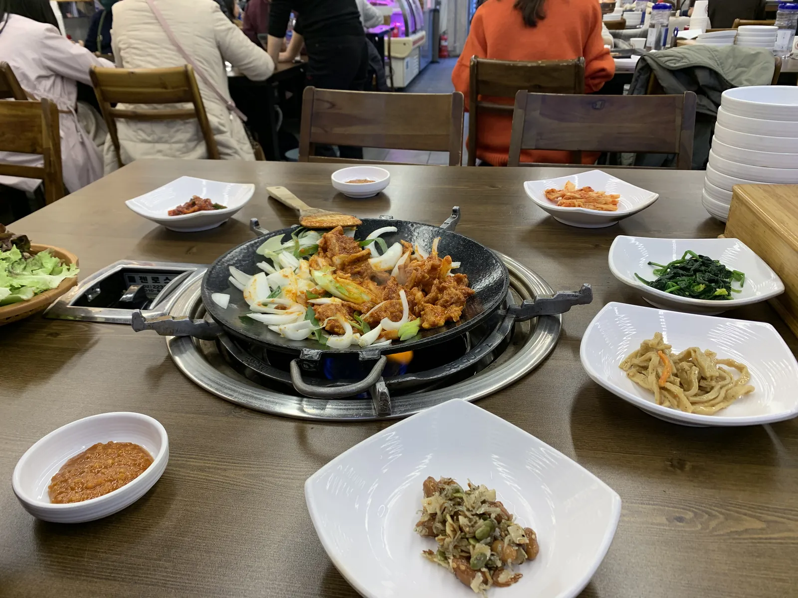 Korėjietiškų pietų stalas su dakgalbi keptuvėje ir gausybe banchan užkandžių