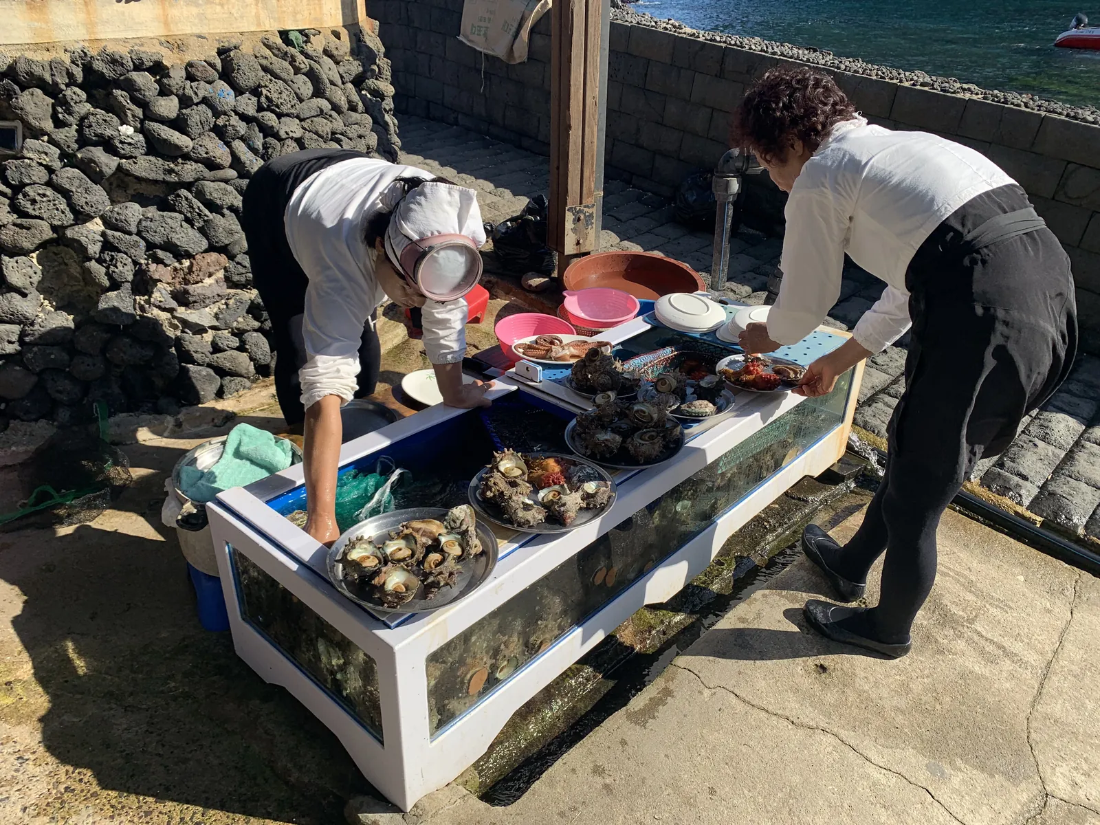 Haenyeo moterys ruošia šviežias jūros gėrybes — abalonus ir jūros ežiukus — prie jūros Jeju saloje
