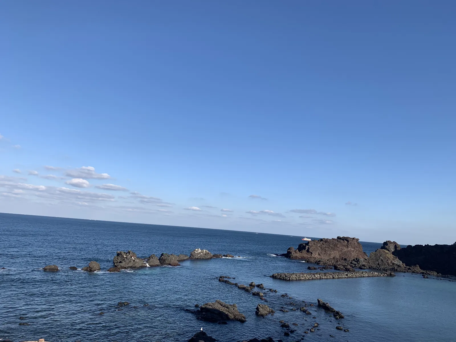 Uolėta Jeju pakrantė su mažomis salelėmis ir ramia jūra