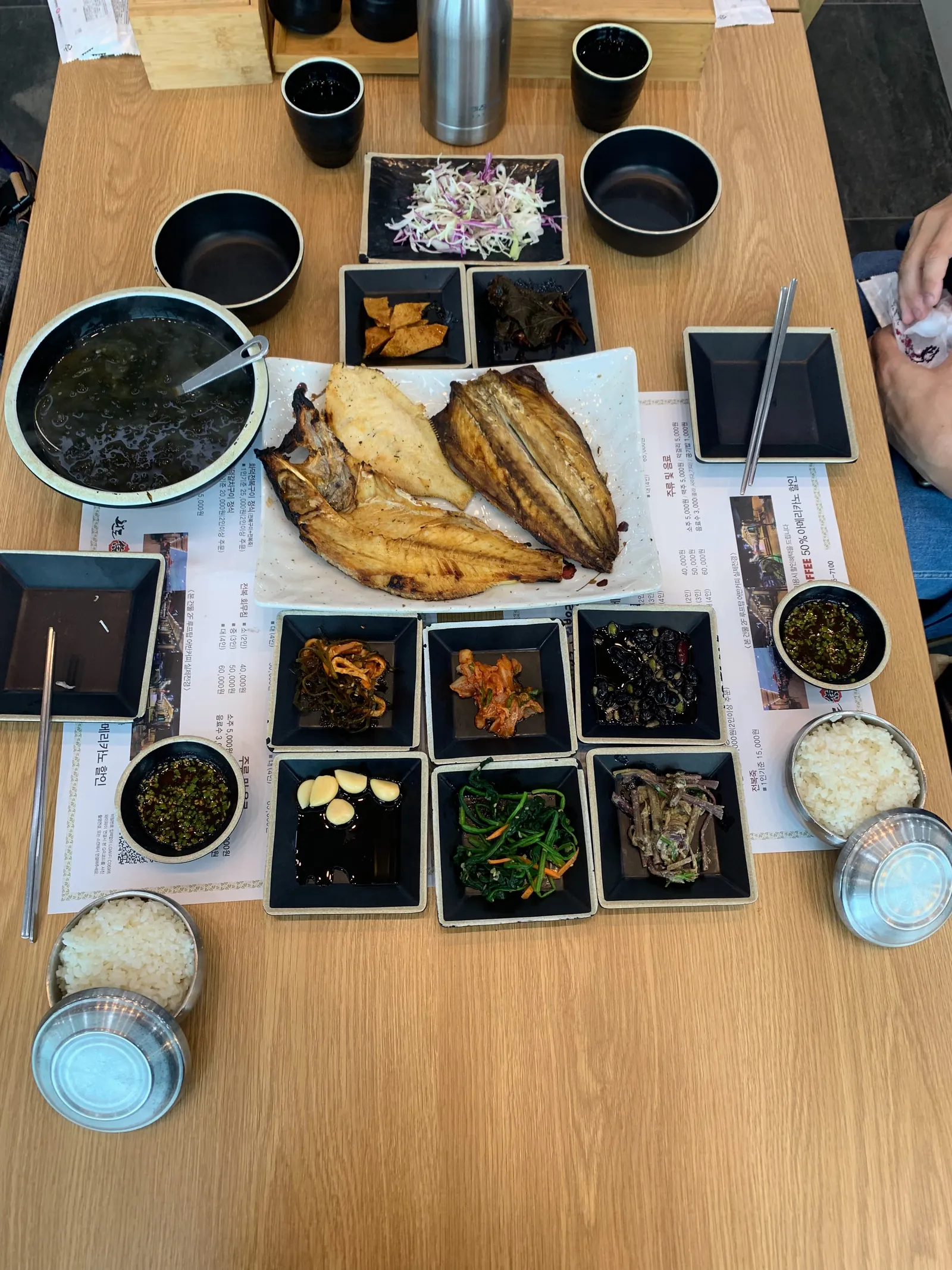 Pajūrio jūros gėrybių vaišės — kepta žuvis ir gausybė banchan priedų